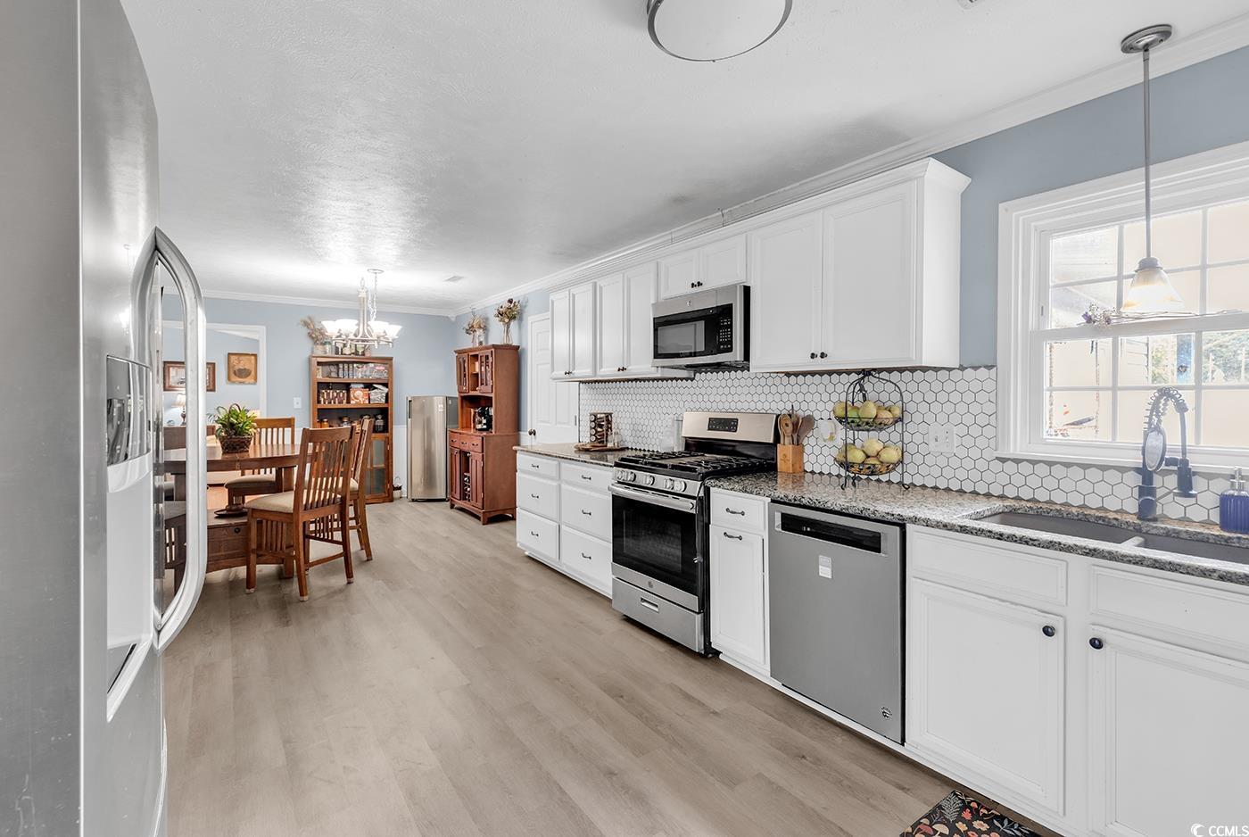 4 Plantation Road Myrtle Beach, SC 29588 - Photo 3 of 40 Kitchen featuring a chandelier, hanging light fixtures, ornamental molding, appliances with stainless steel finishes, and white cabinets