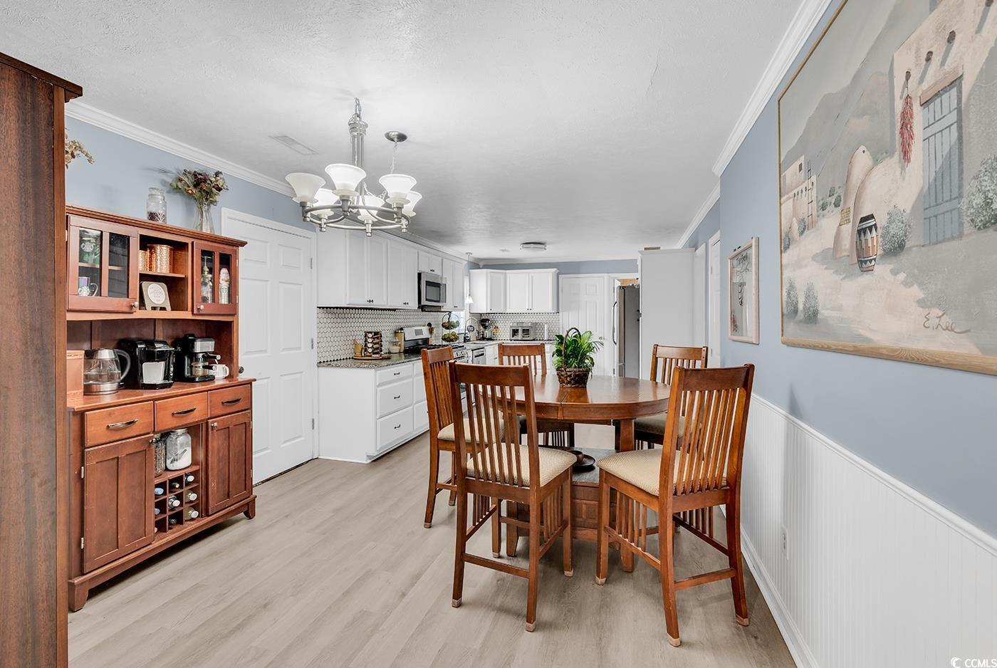 4 Plantation Road Myrtle Beach, SC 29588 - Photo 8 of 40 Dining room featuring ornamental molding, light wood-style floors, wainscoting, and a chandelier