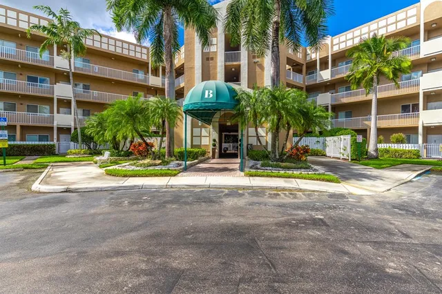 a view of a building with a yard and palm trees