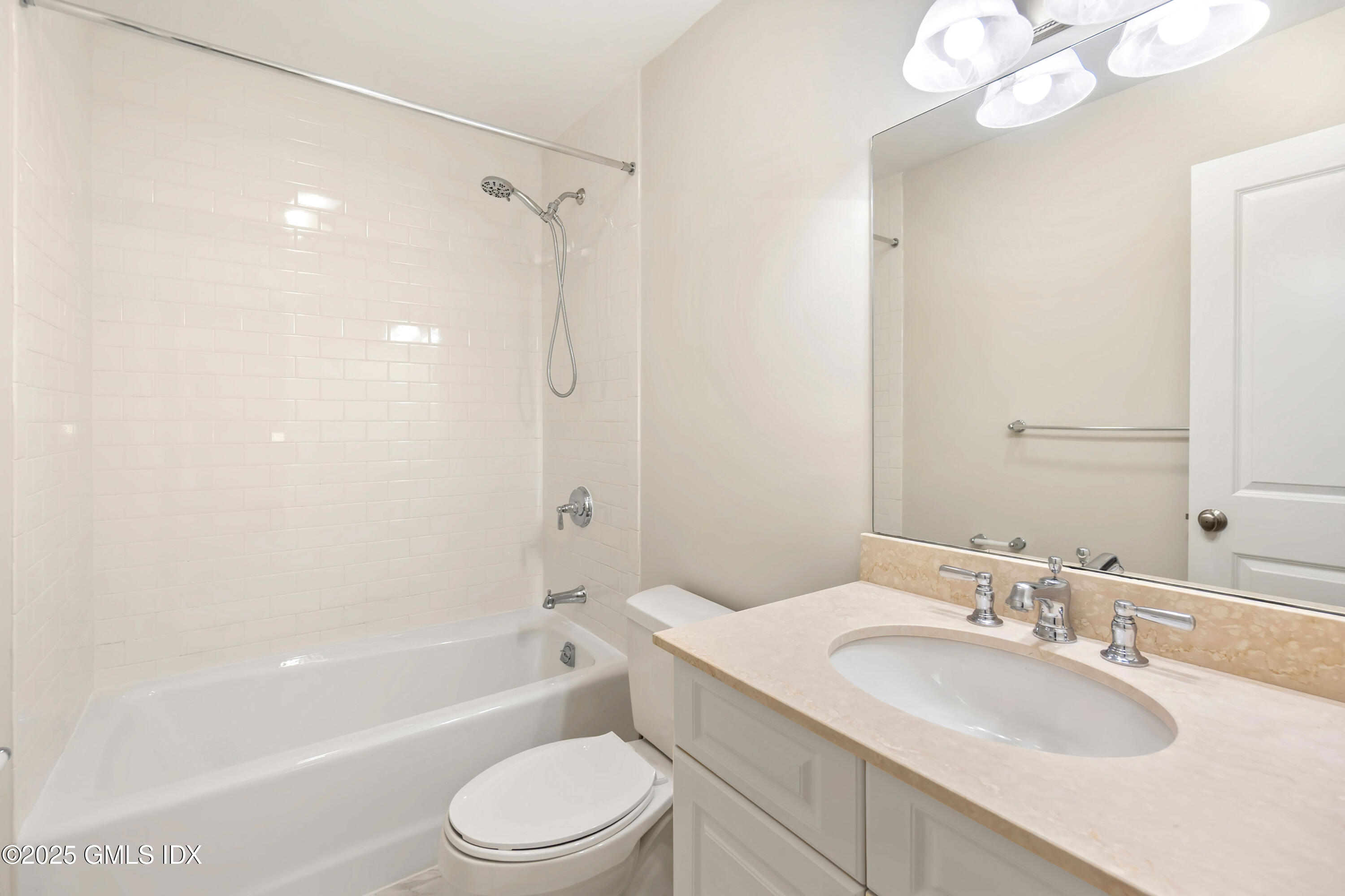 221 Weaver Street, Unit 19C Greenwich, CT 06831 - Photo 14 of 23 a bathroom with a granite countertop sink a toilet a mirror a bathtub and shower