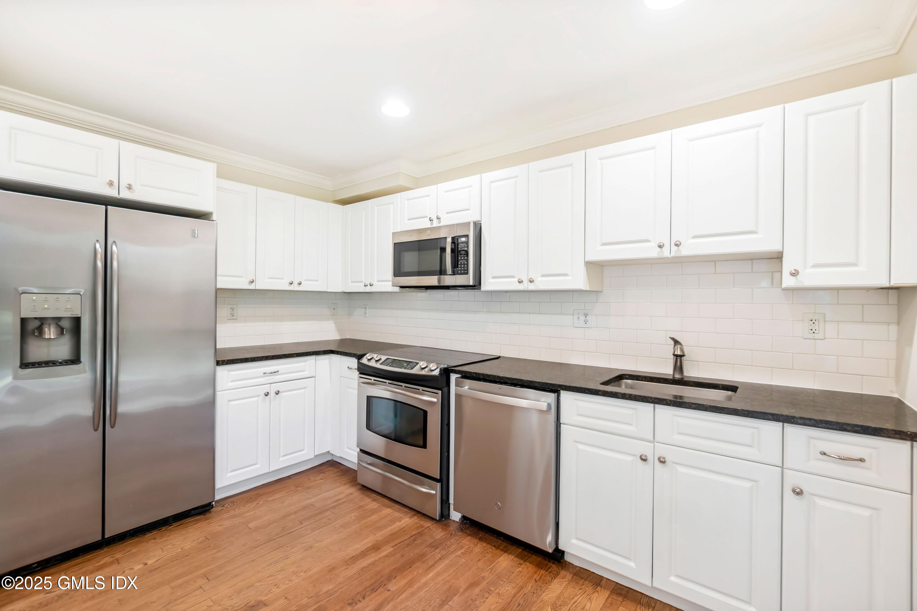221 Weaver Street, Unit 19C Greenwich, CT 06831 - Photo 4 of 23 a kitchen with cabinets stainless steel appliances a sink and wooden floor