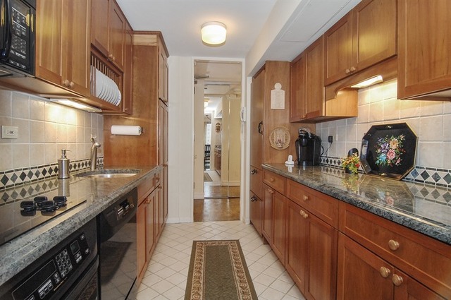 1310 North Ritchie Court, Unit 14C Chicago, IL 60610 - Photo 13 of 22 a kitchen with granite countertop a sink a counter space and cabinets