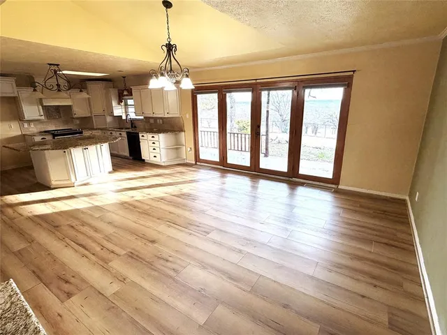 a view of a room with wooden floor and a kitchen