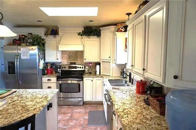 a kitchen with kitchen island granite countertop a sink and cabinets
