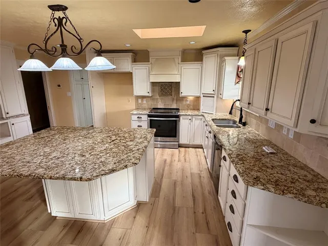 a kitchen with stainless steel appliances granite countertop a stove oven and a wooden floors