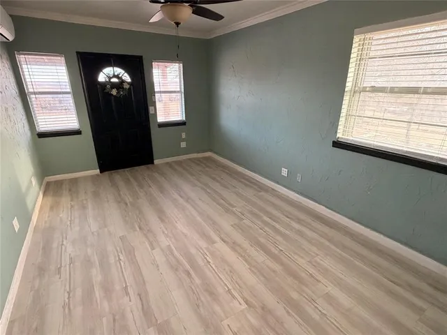 a view of an empty room with wooden floor and a window