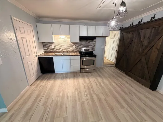 a kitchen with granite countertop wooden floors a refrigerator and stainless steel appliances