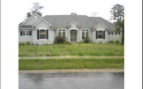 96102 Captains Pointe Road Yulee, FL 32097 - Photo 1 of 1 a view of a white house next to a yard with big trees
