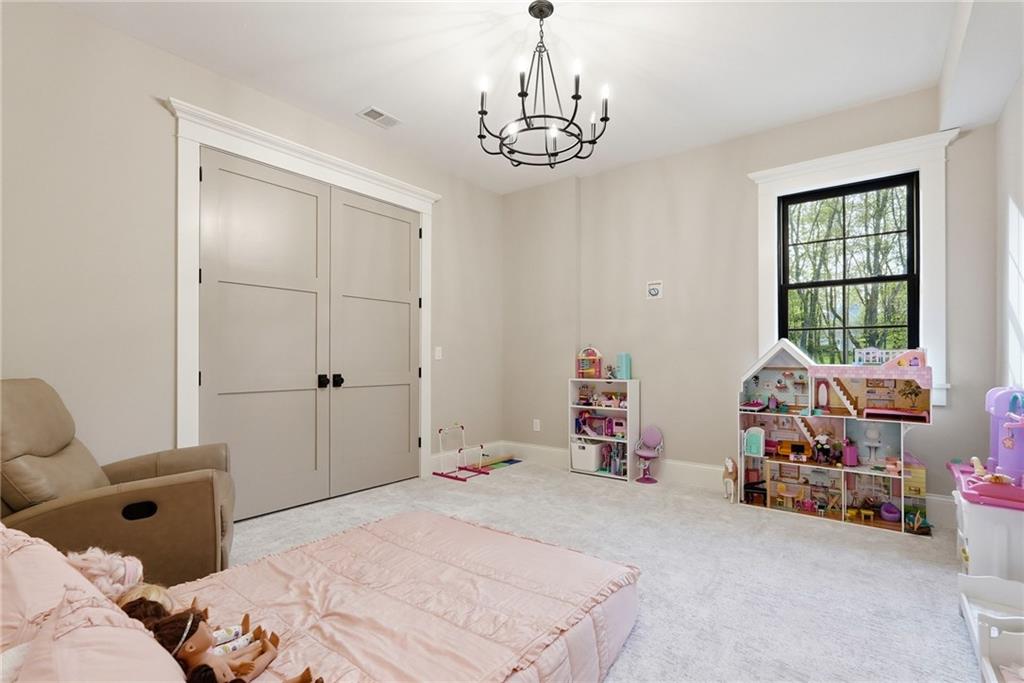 225 Stoup Road Mars, PA 16046 - Photo 38 of 50 The lower level bedroom features a double door closet, statement chandelier, black-framed window with wooded views, and plush carpet — a versatile space well suited for guests, a playroom, or additional living needs.