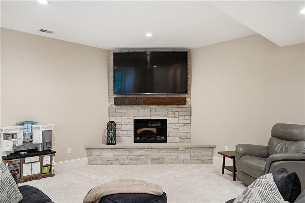 225 Stoup Road Mars, PA 16046 - Photo 41 of 50 The lower level living area features a stone fireplace with a wood mantel, recessed lighting, and plush carpet — a comfortable gathering space that flows directly to the bar and walk-out access.