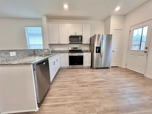 a kitchen with granite countertop a refrigerator stove top oven and sink
