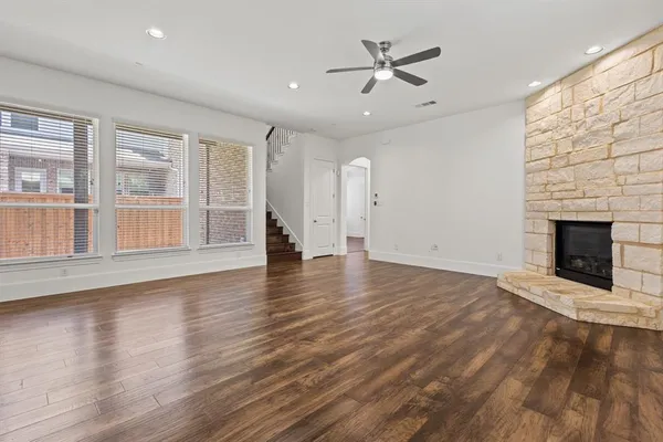 an empty room with wooden floor fireplace and windows