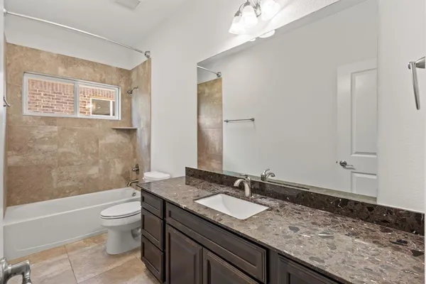 a bathroom with a granite countertop sink a toilet and shower