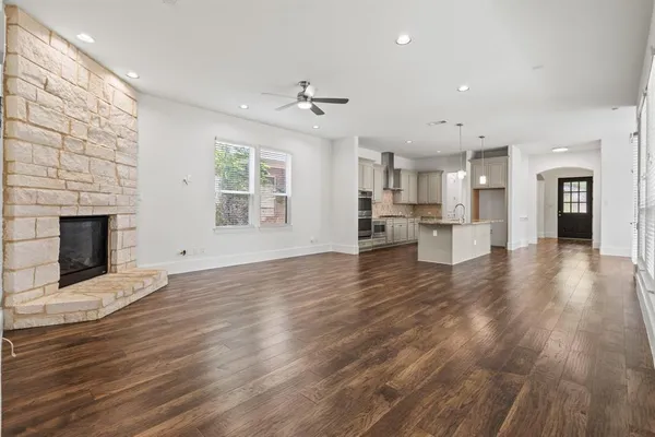 an empty room with wooden floor and a kitchen
