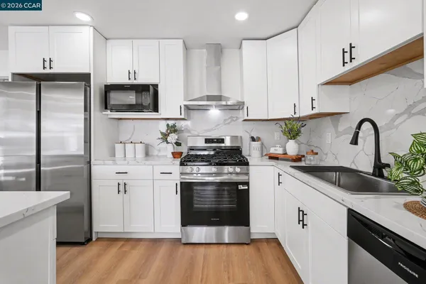 a kitchen with stainless steel appliances granite countertop a stove a sink dishwasher and a refrigerator