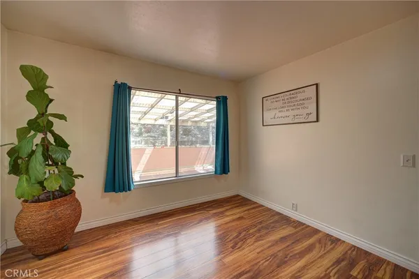 a view of an empty room with wooden floor and a potted plant