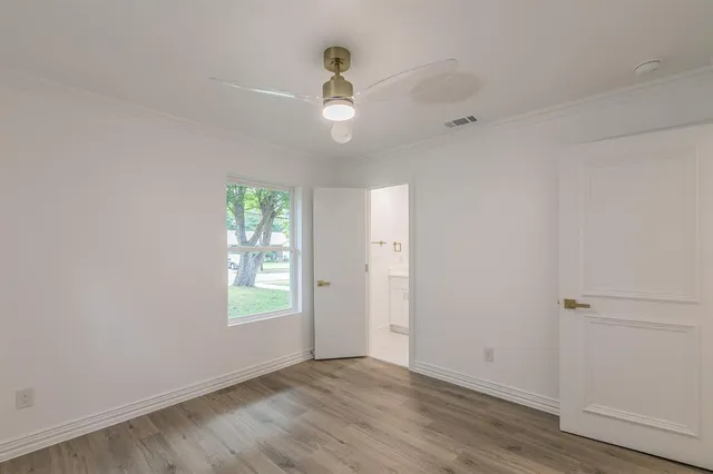an empty room with wooden floor chandelier fan and windows