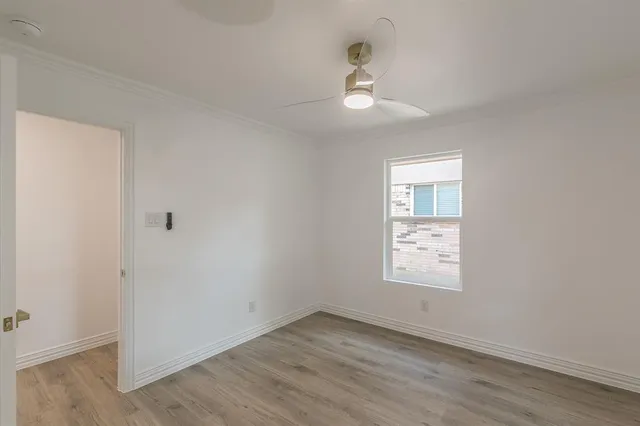 an empty room with wooden floor fan and window