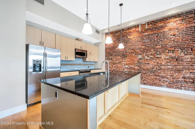 a kitchen with stainless steel appliances granite countertop a sink a stove and a wooden floors