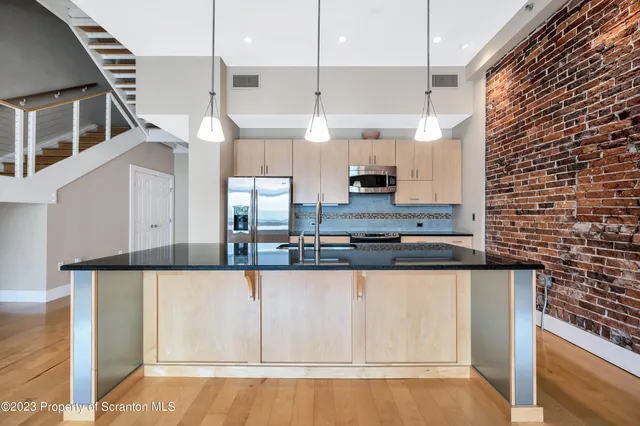 a kitchen with stainless steel appliances granite countertop a sink a stove and a wooden floors
