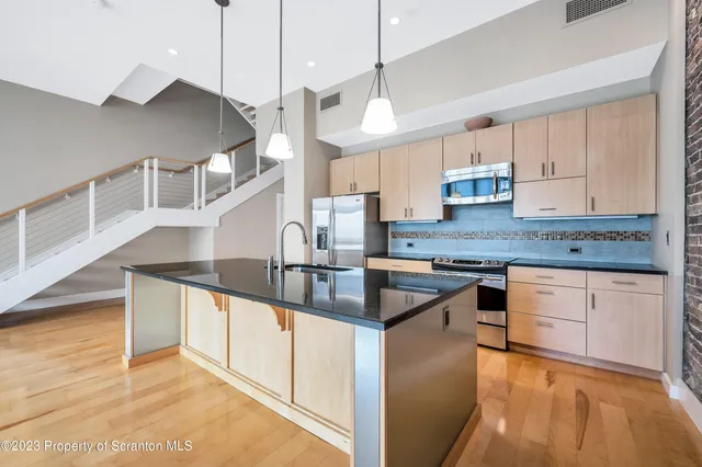 a kitchen with stainless steel appliances granite countertop a sink a window and a counter top space