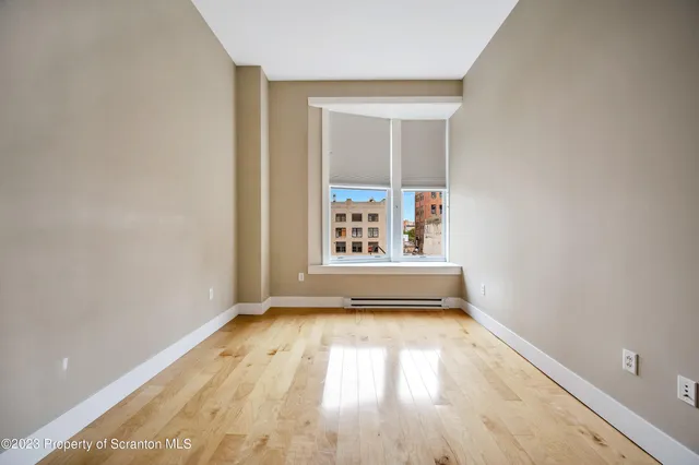 a view of empty room with wooden floor