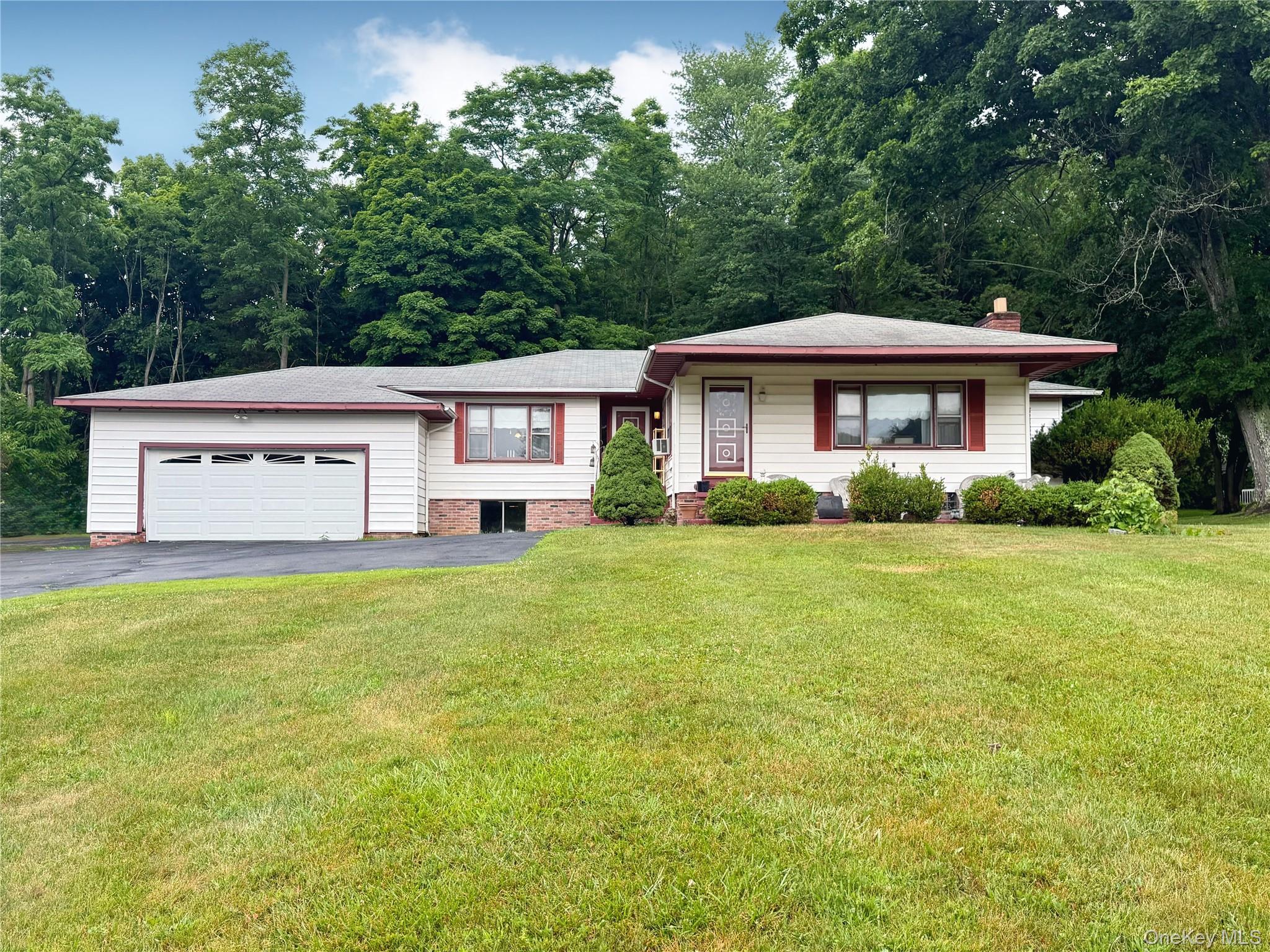 Ranch-style residence featuring a white siding exterior with brick accents, an attached garage, and a paved driveway