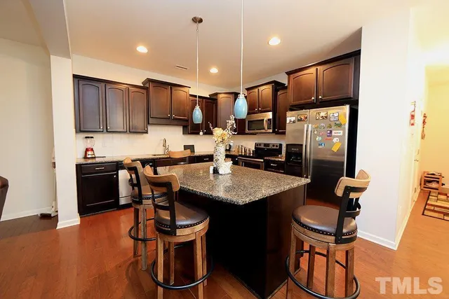a kitchen with stainless steel appliances granite countertop a sink a stove a refrigerator and cabinets