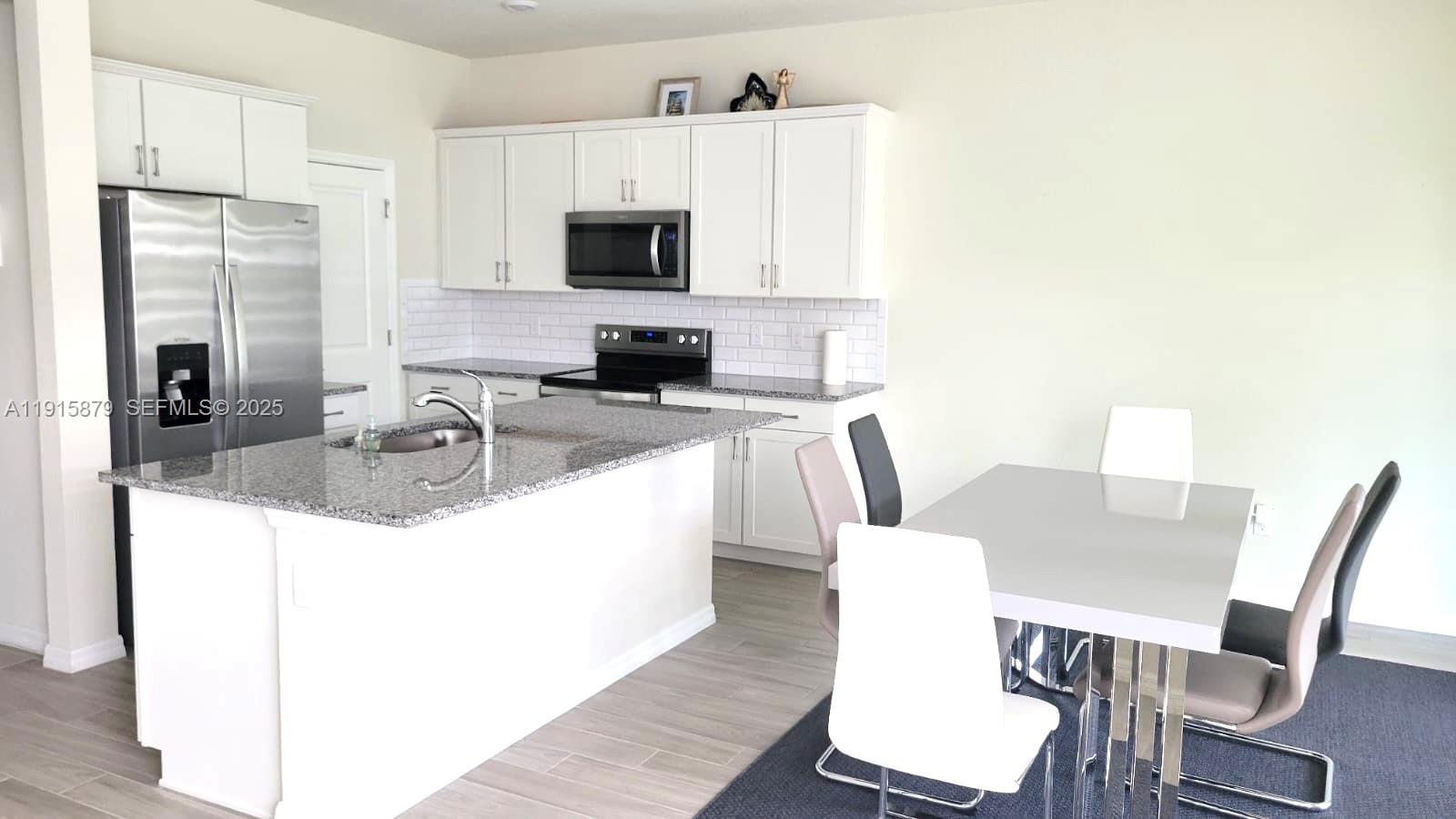 4164 Ficus Street Hollywood, FL 33021 - Photo 11 of 16 a kitchen with stainless steel appliances granite countertop a sink a microwave refrigerator and chairs