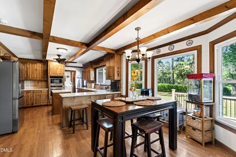a room with stainless steel appliances granite countertop table chairs and a large window