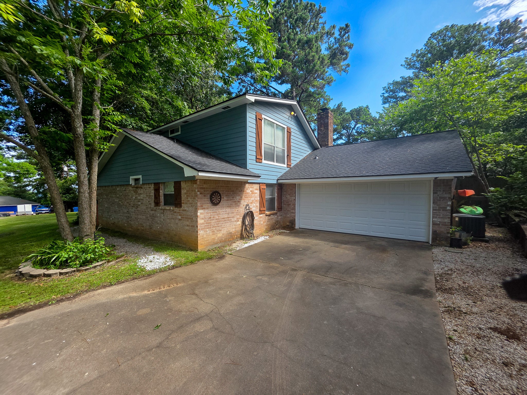 145 Cypress Road Livingston, TX 77351 - Photo 14 of 16 This charming two-story home features a mix of brick and siding with a spacious driveway leading to a two-car garage. It's set in a lush, green environment with mature trees, offering a peaceful and private atmosphere.