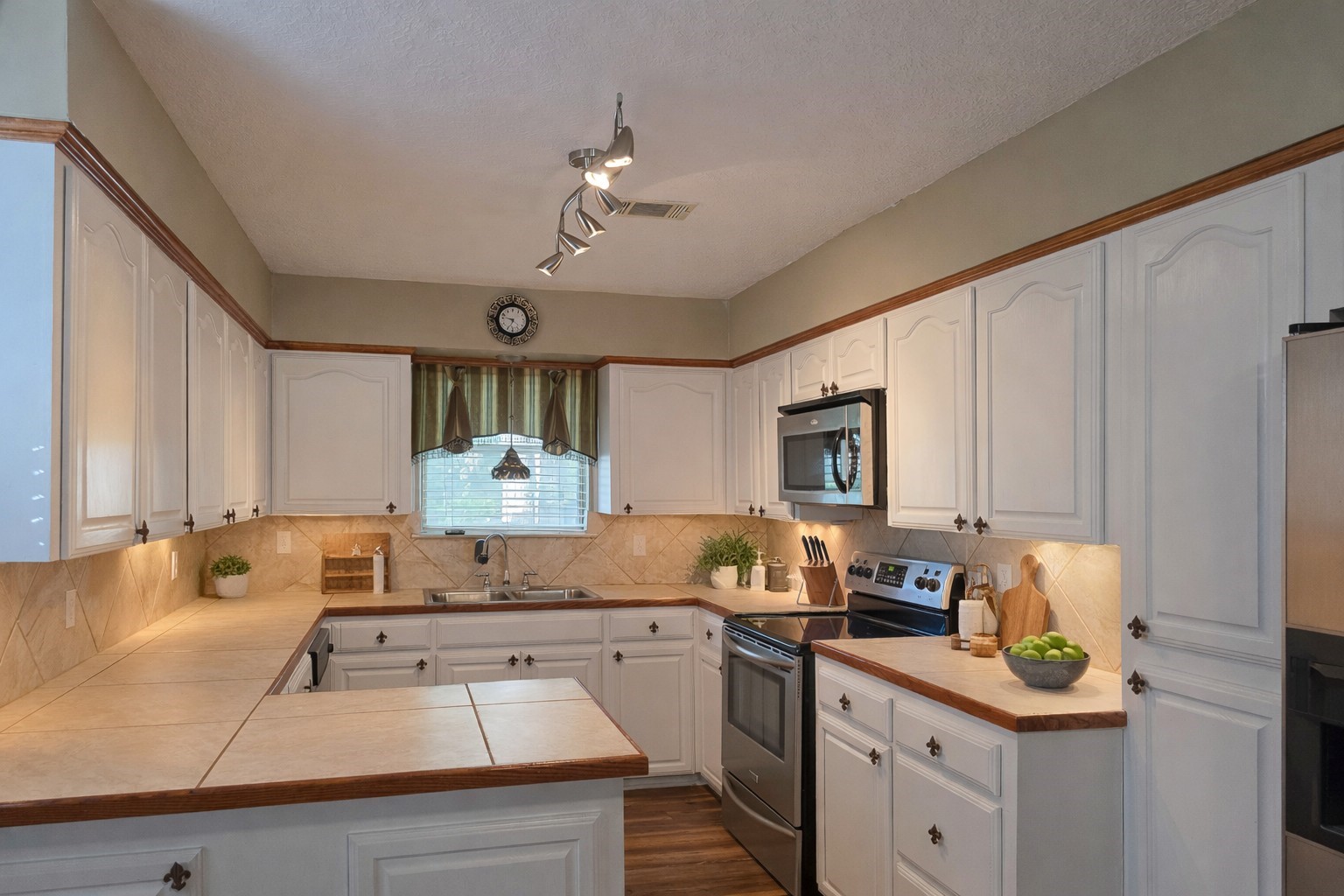 145 Cypress Road Livingston, TX 77351 - Photo 2 of 16 This kitchen features ample white cabinetry, stainless steel appliances, and warm tile countertops. The space is well-lit while still offers a cozy, inviting atmosphere.