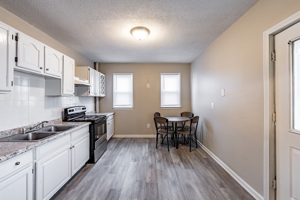 254-256 Main Street Springfield, MA 01151 - Photo 24 of 34 a kitchen with stainless steel appliances granite countertop wooden floors a stove and white cabinets