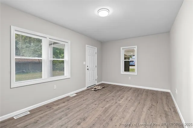 a view of an empty room with a window and wooden floor