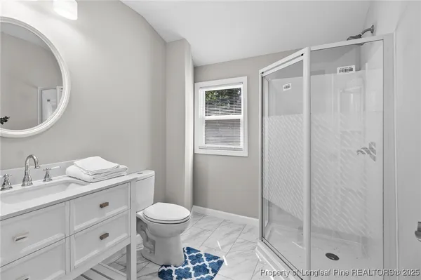 a bathroom with a granite countertop sink toilet a mirror a shower and vanity