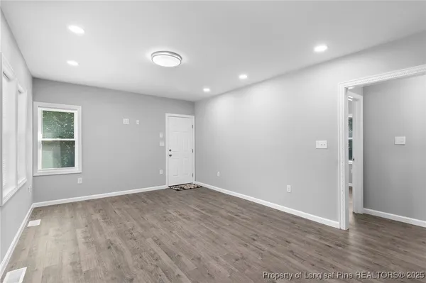 an empty room with wooden floor and windows