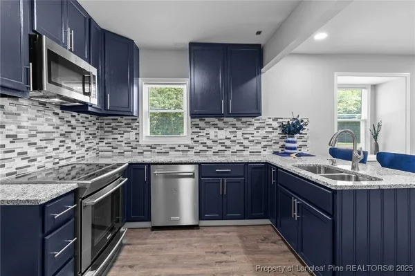 a kitchen with stainless steel appliances granite countertop sink stove microwave and cabinets