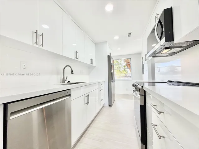 a kitchen with granite countertop a sink stainless steel appliances and cabinets