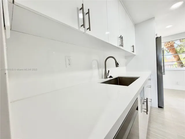a kitchen with a sink a counter top space and stainless steel appliances