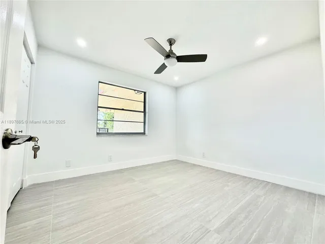 an empty room with wooden floor ceiling fan and windows