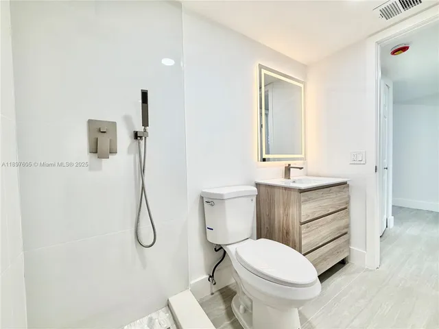 a bathroom with a sink vanity mirror and toilet