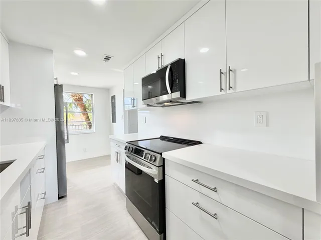 a kitchen with stainless steel appliances white cabinets and a stove top oven