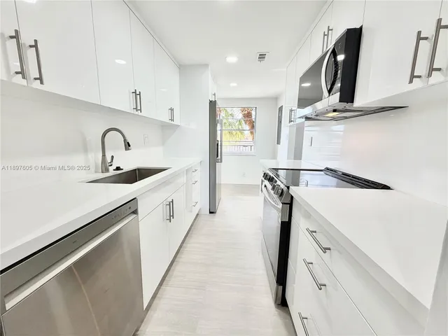 a kitchen with white cabinets and sink