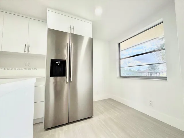 a view of a refrigerator in kitchen and a cabinets