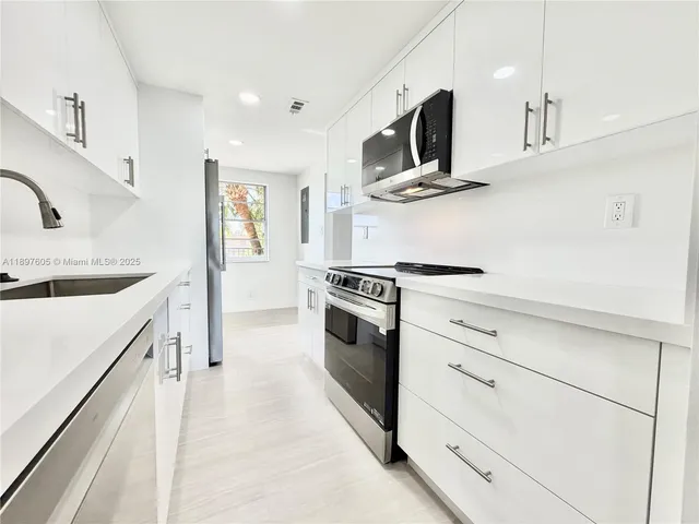 a kitchen with white cabinets and stainless steel appliances