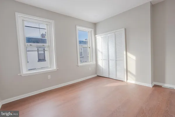 an empty room with wooden floor fireplace and windows