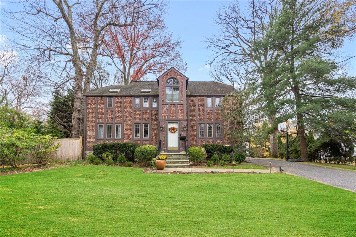 View of front of house featuring driveway, a front yard, fence, and brick siding
