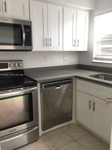 a kitchen with granite countertop white cabinets and stainless steel appliances