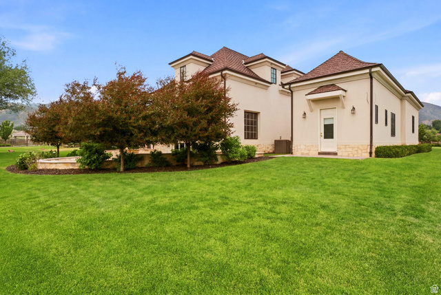 71 Farm Road Midway, UT 84049 - Photo 80 of 92 Spacious exterior grounds featuring expansive green lawn, mature trees, stucco facade, stone detailing, and a shingle roof