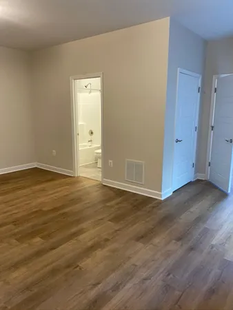 a view of an empty room with wooden floor and window